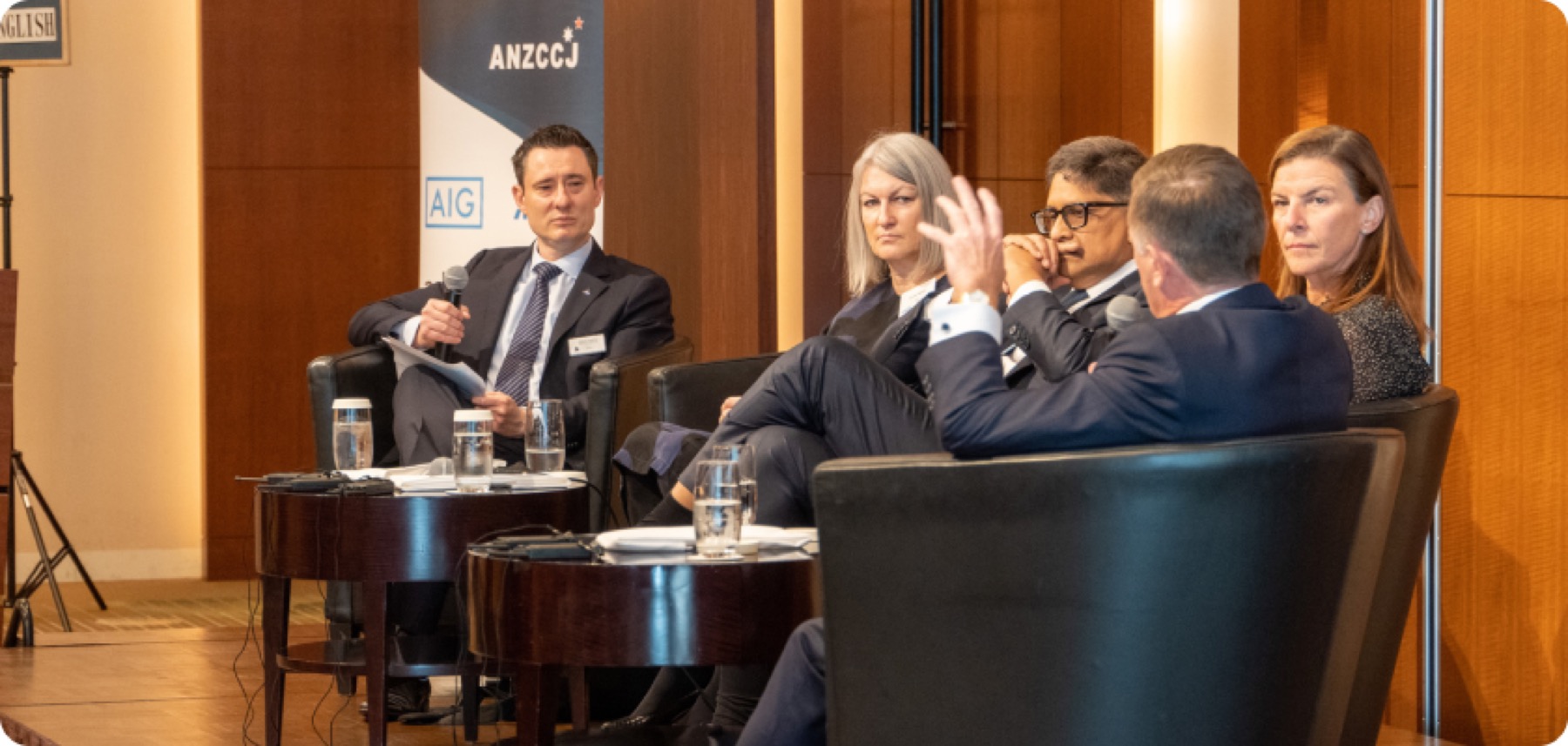 A panel discussion in armchairs in front of an ANZCCJ banner